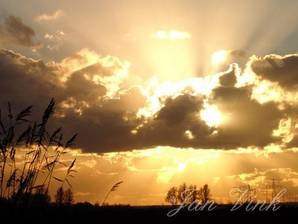 Zon door dreigende wolken bij Krommeniedijk